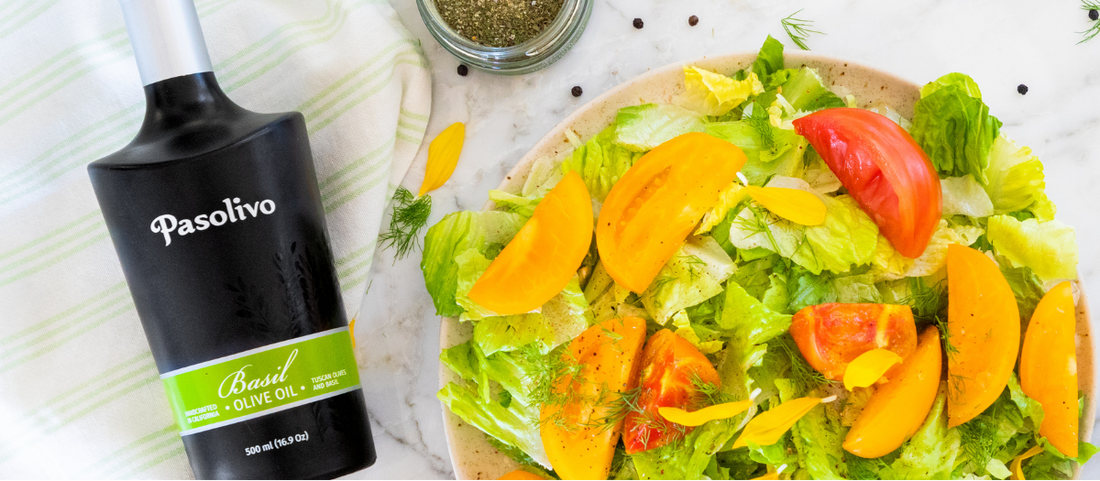 Pasolivo Basil Olive Oil and Spring Blend Seasoning next to a bright, fresh summer salad with lettuce, tomatoes, and fresh herbs.