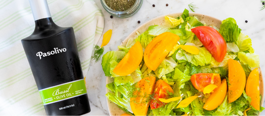 Pasolivo Basil Olive Oil and Spring Blend Seasoning next to a bright, fresh summer salad with lettuce, tomatoes, and fresh herbs.