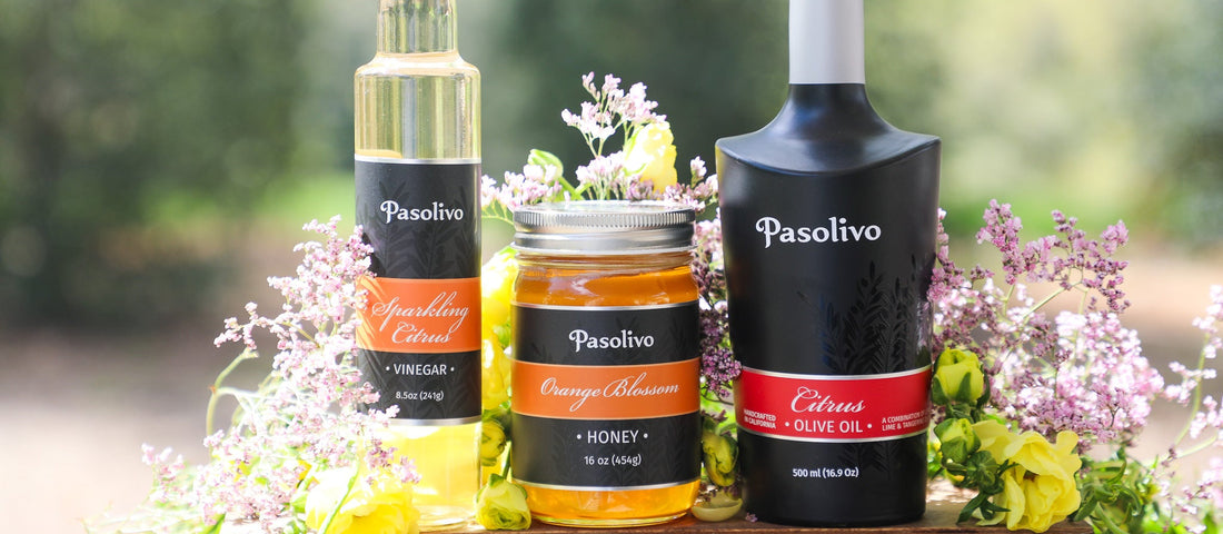 Pasolivo olive oil salad dressing gift set with citrus olive oil, sparkling citrus vinegar, and orange blossom honey surrounded by fresh blooms. 