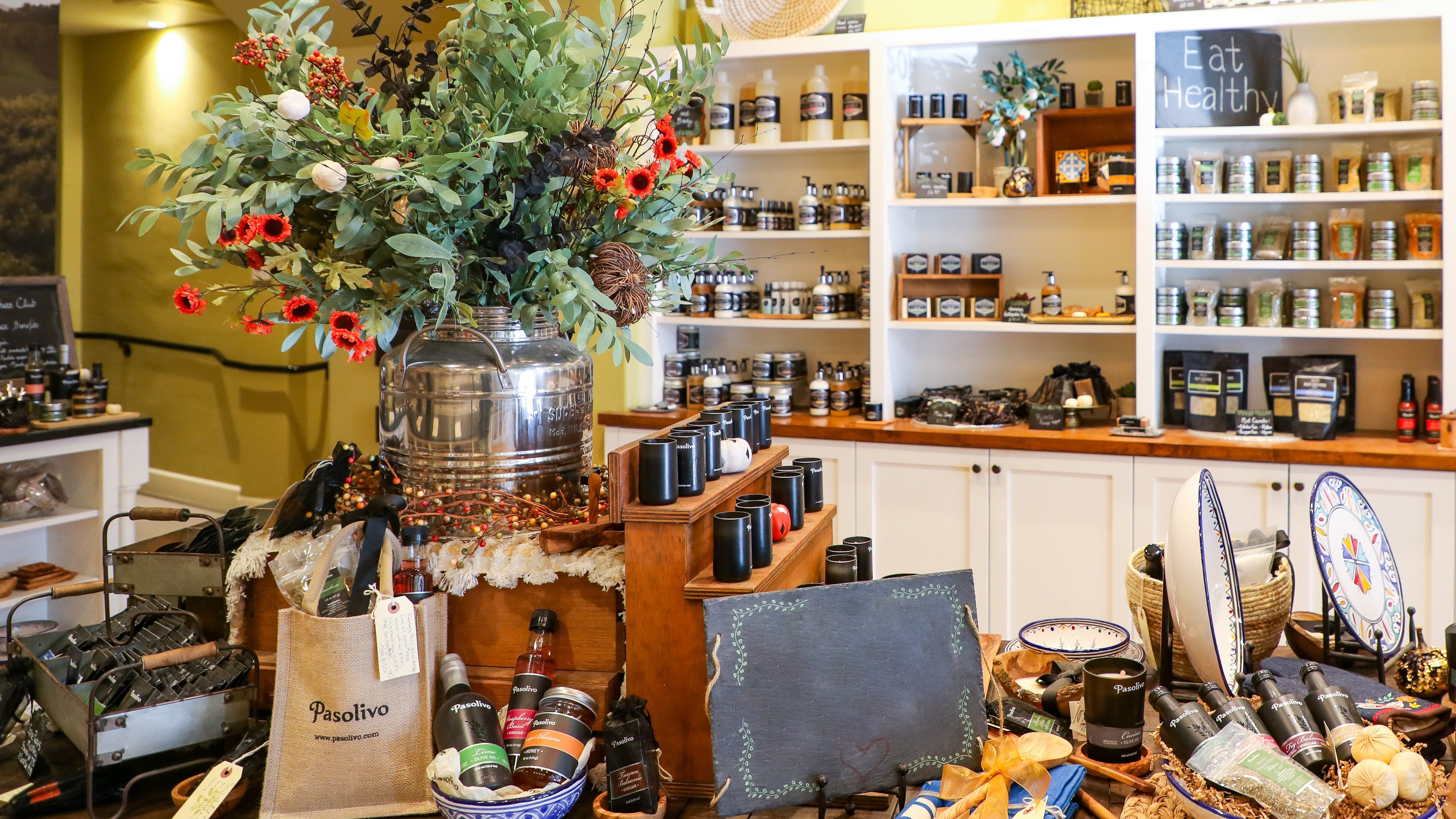 Interior of a store with shelves stocked with products, a vase of flowers, and various items on display.