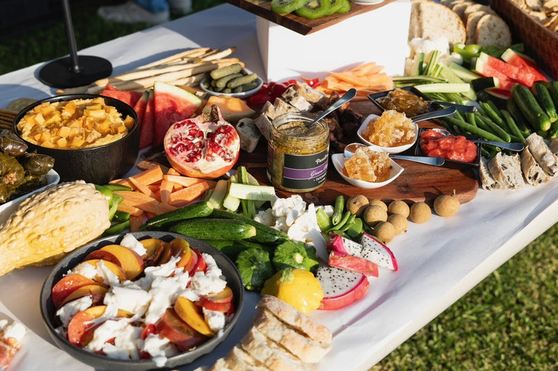 Outdoor setting with a table full of assorted food items on a white tablecloth.
