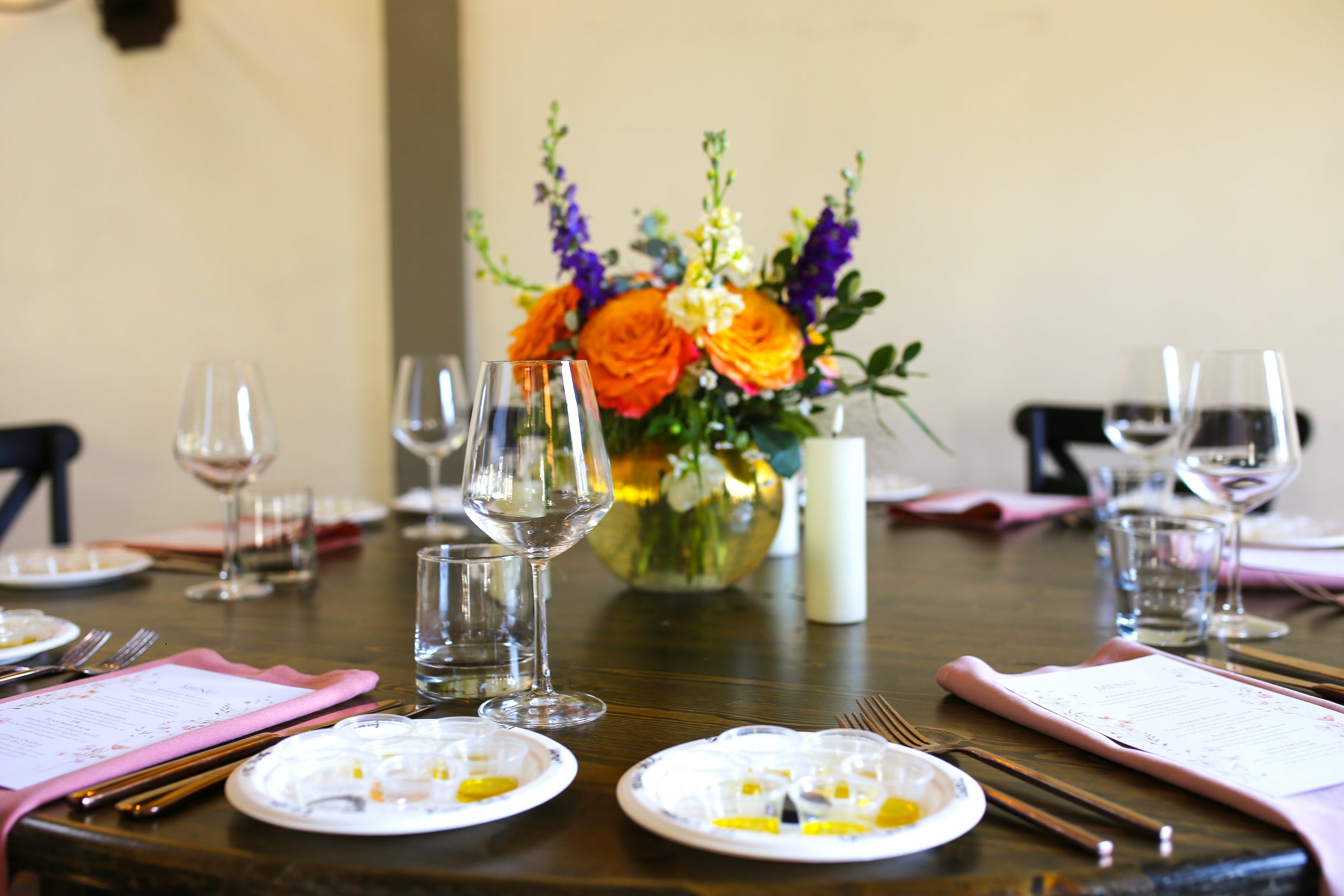 Dining table set with plates, glasses, and a floral centerpiece.