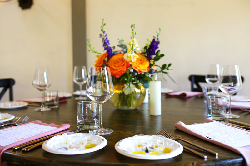 Dining table set with plates, glasses, and a floral centerpiece.