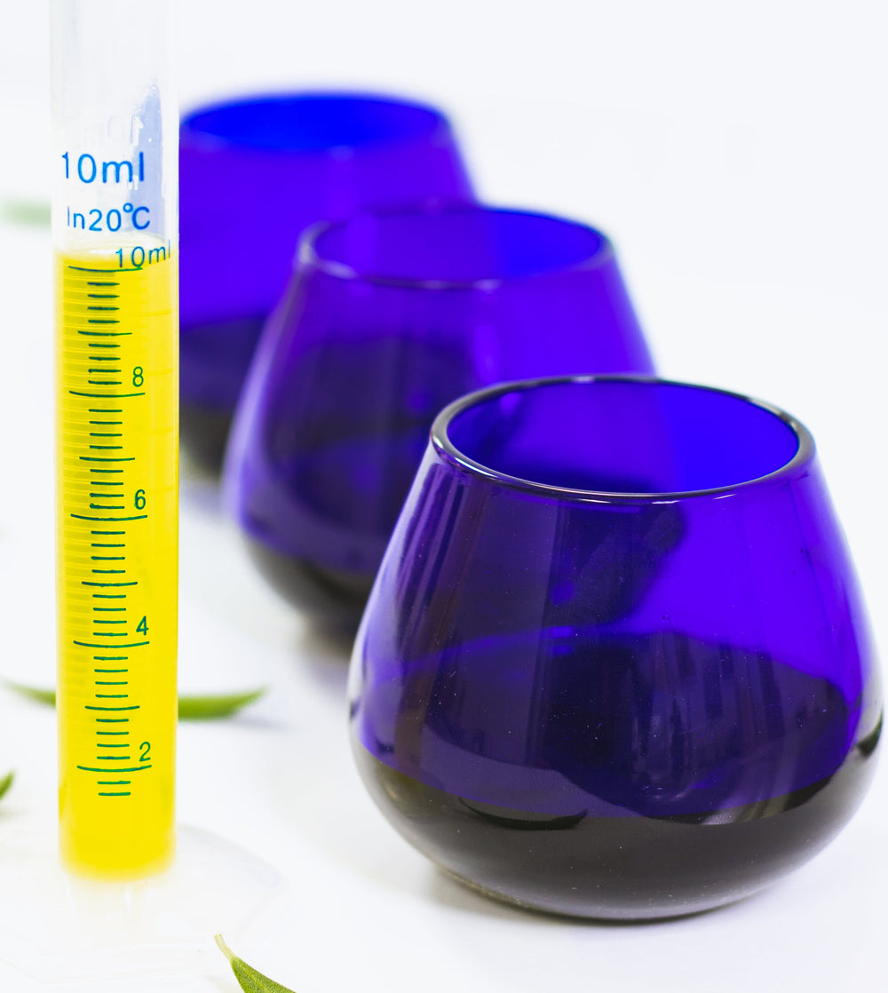Three blue glass tumblers with an olive oil beaker on a white background