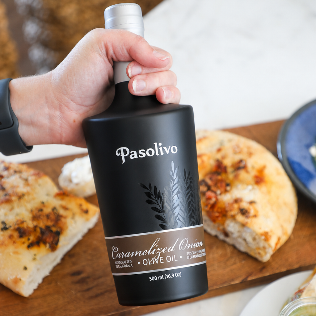 Pasolivo Caramelized Onion Olive Oil next to tomato and parmesan focaccia bread.