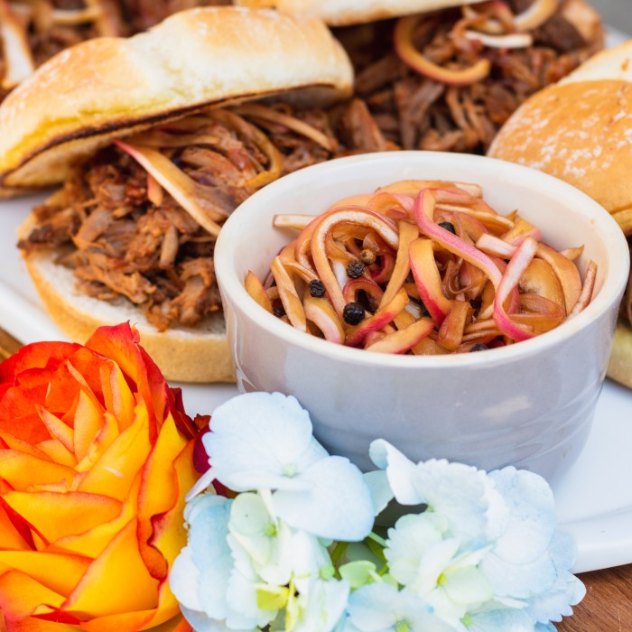Pasolivo Pickled Red Onions Recipe plated with pulled pork sandwiches next to flowers