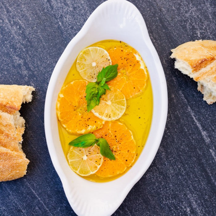 Pasolivo Oranges Recipe next to a piece of baguette and garnished with fresh herbs