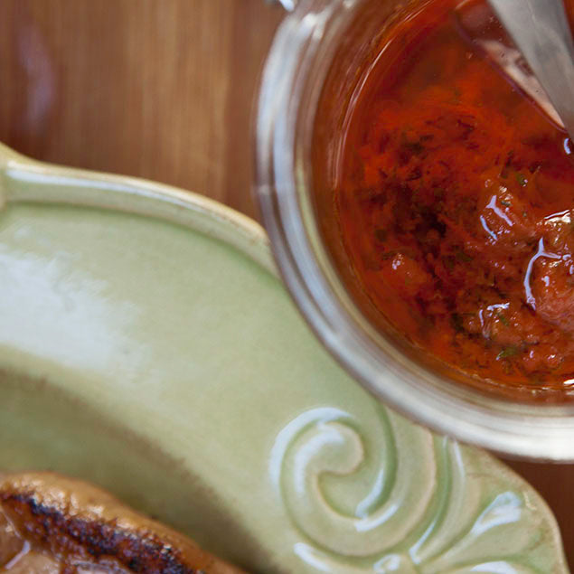 Pasolivo California Blend Olive Oil Marinade Recipe in a jar with a spoon resting on table next to a green plate